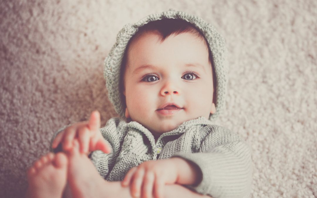 baby on gray knit hooded clothes lying on carpet
